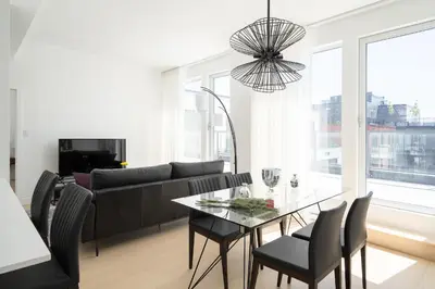 a living room with a black couch and a glass table at Le Se7t Penthouses in Montréal