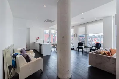a living room with white furniture and a column at Le Se7t Penthouses in Montréal