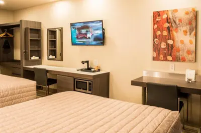 a hotel room with two beds and a desk at Le Chabrol Hotel & Suites in Montréal
