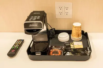 a coffee maker sitting on a counter next to a remote control at Le Chabrol Hotel & Suites in Montréal
