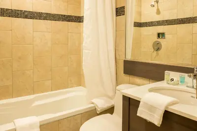 a bathroom with a tub and a toilet and a sink at Le Chabrol Hotel & Suites in Montréal