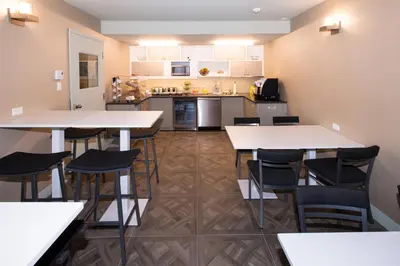 a kitchen with white tables and chairs in a room at Le Chabrol Hotel & Suites in Montréal