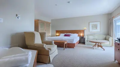 a hotel room with a bed and a couch and chairs at Auberge Handfield et Spa in Saint-Marc-sur-Richelieu