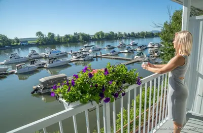 a woman standing on a balcony overlooking a marina at Auberge Handfield et Spa in Saint-Marc-sur-Richelieu