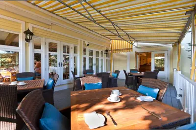 a restaurant with wooden tables and chairs on a patio at Auberge West Brome in West Brome