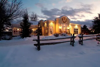 a house in the snow with a bench in front of it at Auberge West Brome in West Brome
