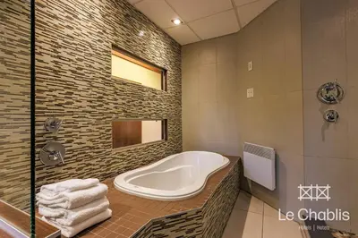 a bathroom with a tub and a shower at Hotel Le Chablis Cadillac in Montréal