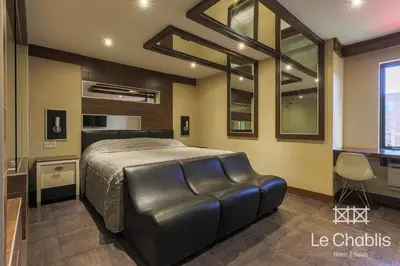 a bedroom with a large bed with a black leather couch at Hotel Le Chablis Cadillac in Montréal