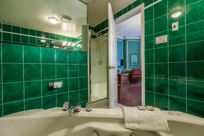 a green tiled bathroom with a tub and a sink at Hotel Chateau de l'Argoat in Montréal