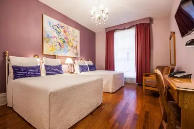 a hotel room with two beds and a desk with a computer at Hotel Chateau de l'Argoat in Montréal