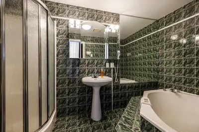 a bathroom with green tiled walls and a sink and tub at Hotel Chateau de l'Argoat in Montréal