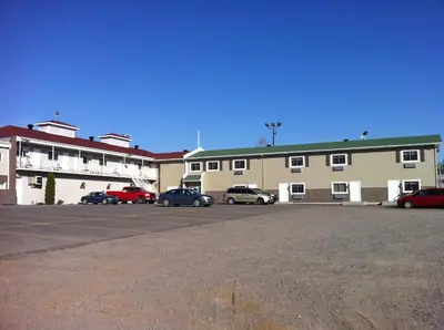 a large building with cars parked in a parking lot at Motel le Phare in Plessisville