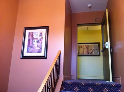 a hallway with a staircase with a mirror and a painting at Motel le Phare in Plessisville
