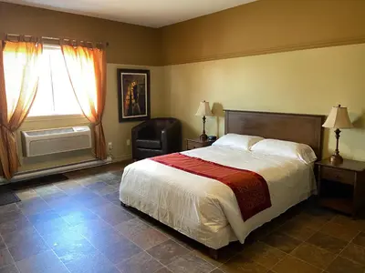a bedroom with a bed and a chair and a window at Motel le Phare in Plessisville