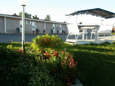 a boat with an umbrella and flowers in a yard at Motel Normandie in Louiseville