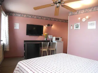 a bedroom with a bed and a desk and a tv at Motel Normandie in Louiseville