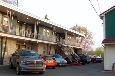 a building with cars parked in a parking lot at Motel Saint-Hilaire in Mont-Saint-Hilaire