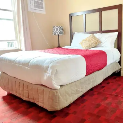 a large bed in a bedroom with a red carpet at Motel Saint-Hilaire in Mont-Saint-Hilaire