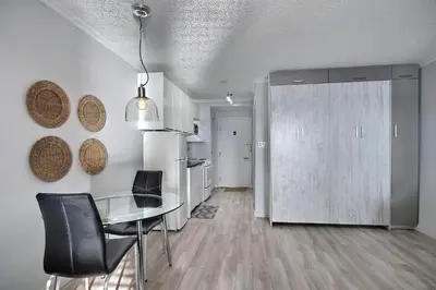 a dining room with a glass table and a kitchen at Location Tourisme Estrie - Oberge du Village in Magog-Orford