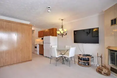 a kitchen and dining room with a table and a tv at Location Tourisme Estrie - Oberge du Village in Magog-Orford