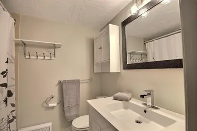 a bathroom with a sink and a toilet and a mirror at Location Tourisme Estrie - Oberge du Village in Magog-Orford