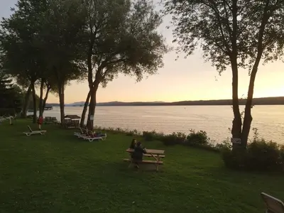 a group of people sitting on benches by the water at Location Tourisme Estrie - Oberge du Village in Magog-Orford