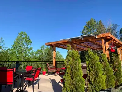 a wooden pergola with chairs and a table on a patio at Le Loft Riverstone CITQ 3O1849 in Saint Pierre de Broughton