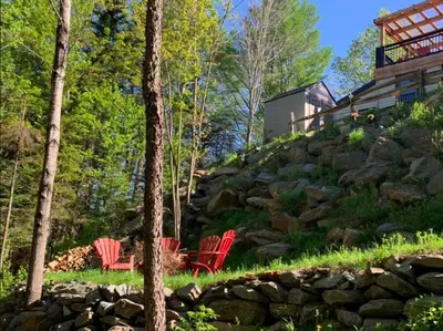 two red chairs sitting next to a rock wall at Le Loft Riverstone CITQ 3O1849 in Saint Pierre de Broughton
