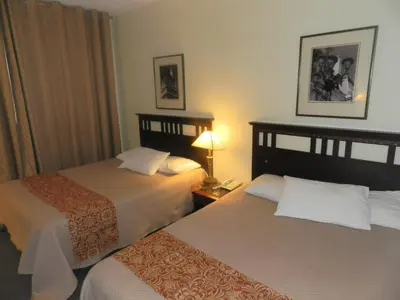 a hotel room with two beds and a lamp at L'Auberge de l'Aeroport Inn in Dorval