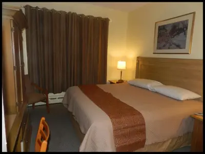 a hotel room with a bed and a chair at L'Auberge de l'Aeroport Inn in Dorval