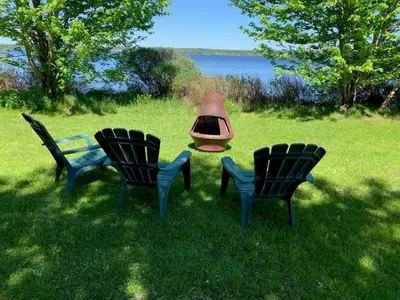 three chairs and a fire pit in the grass at La Grange sur le Lac App A et B in Saint Romain