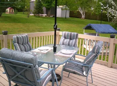 a table and chairs on a deck with an umbrella at Gîte Au p'tit bonheur B&B in Coaticook