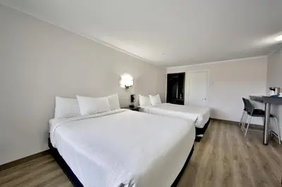 a hotel room with two beds and a desk at Motel Newstar Laval in Laval