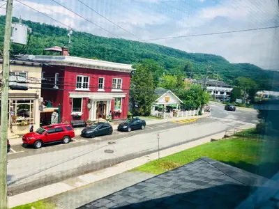a red building with cars parked on the side of a street at Le « Lake View » de la Suite North Hatley in North Hatley