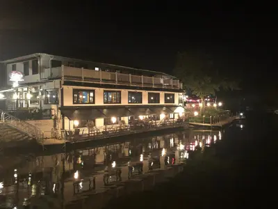 a building with lights on the water at night at Le « Lake View » de la Suite North Hatley in North Hatley