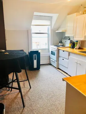 a kitchen with white cabinets and a table and a window at Le « Lake View » de la Suite North Hatley in North Hatley