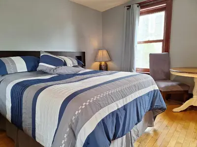 a bedroom with a bed and a chair and a window at Le 100 St-Laurent in Louiseville