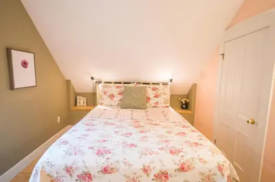 a bedroom with a bed with a floral bedspread at Boisé Rivière in Bolton-Est
