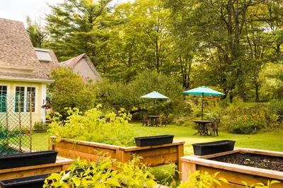 a garden with tables and umbrellas in a yard at Boisé Rivière in Bolton-Est
