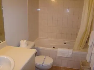 a bathroom with a toilet and a tub and a sink at Hotel Motel Granby in Granby
