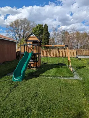 a playground with a green slide in a yard at Hotel Motel Granby in Granby