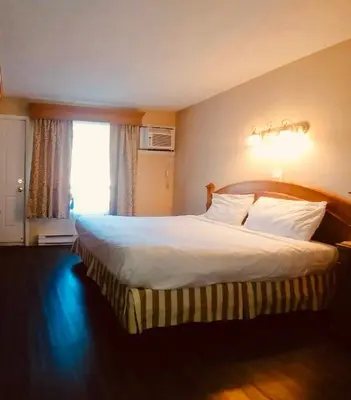 a bedroom with a large white bed with a window at Hotel Motel Granby in Granby