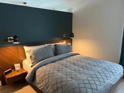 a bedroom with a large bed with a blue wall at Square Victoria Maison Hôtelière in East Angus