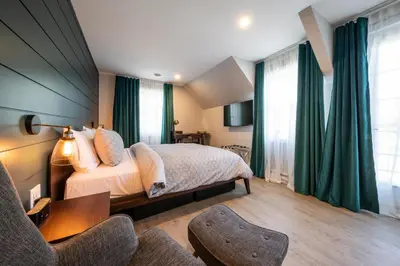 a bedroom with a bed and a table and chairs at Square Victoria Maison Hôtelière in East Angus