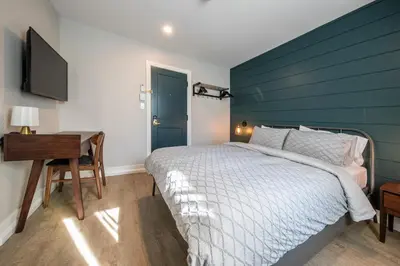 a bedroom with a bed with a blue headboard and a desk at Square Victoria Maison Hôtelière in East Angus