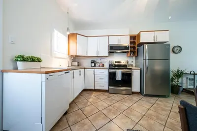 a kitchen with white cabinets and stainless steel appliances at Square Victoria Maison Hôtelière in East Angus