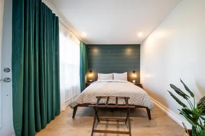 a bedroom with a bed and a green curtain at Square Victoria Maison Hôtelière in East Angus