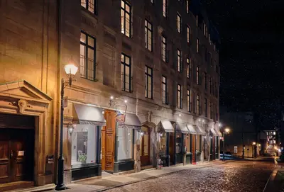 a city street with a building at night at Hotel Bonaparte in Montréal