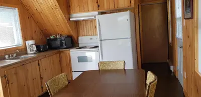 a kitchen with a table and a white refrigerator at Pourvoirie Stéphane Marin in Maskinongé