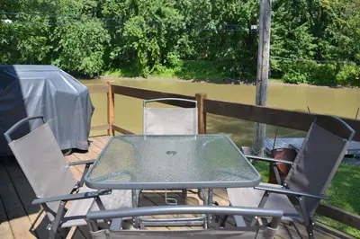 a table and chairs on a deck with a view of a river at Pourvoirie Stéphane Marin in Maskinongé